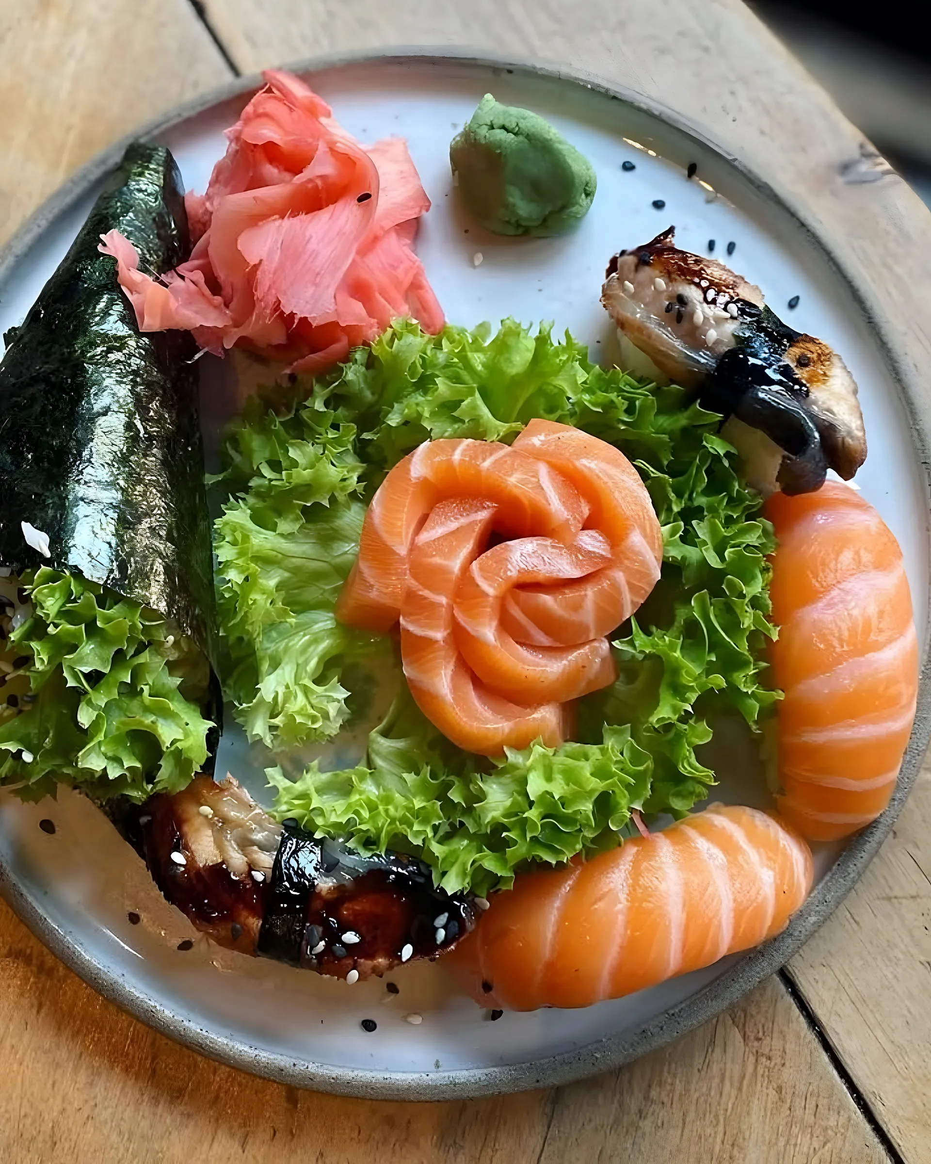 Zalmroos met sla, temaki en unagi op een bord