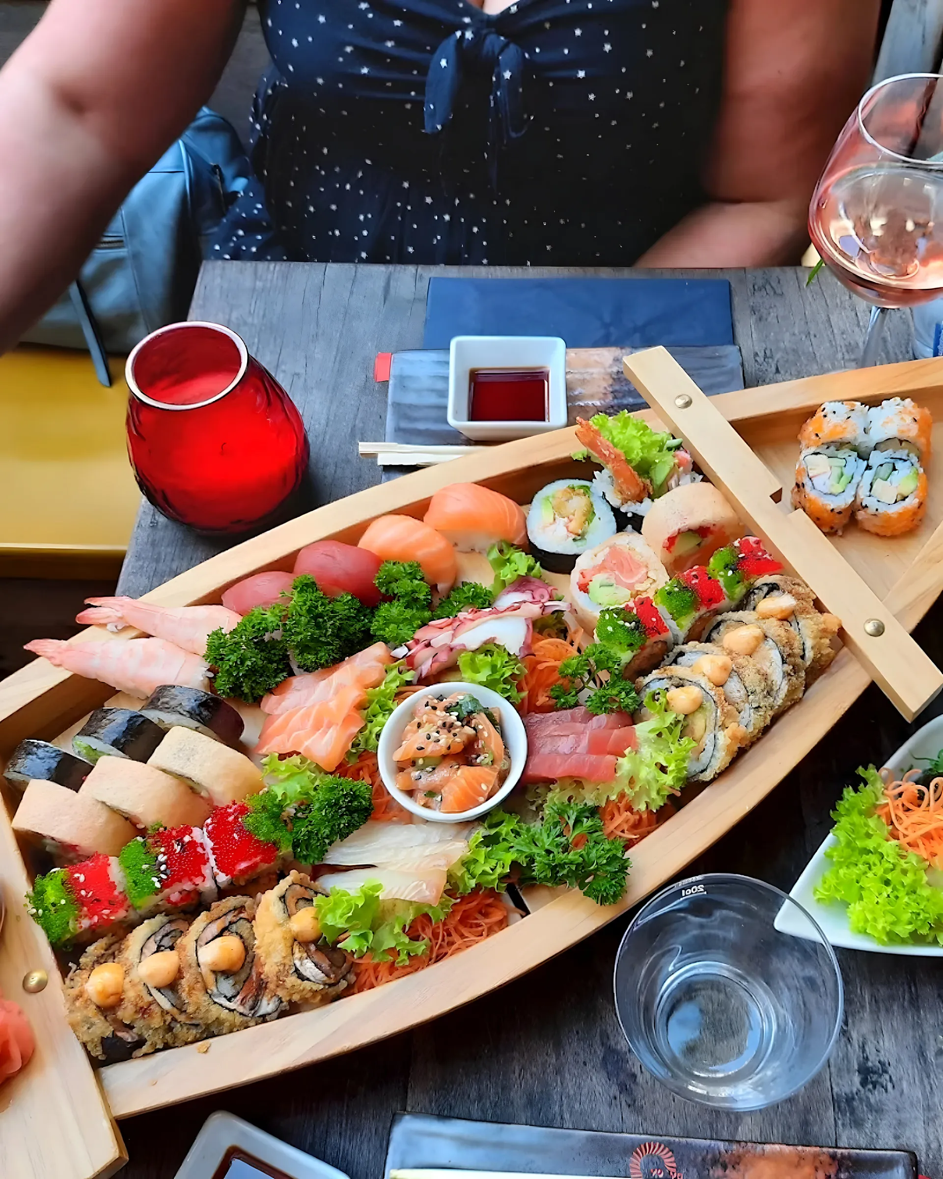 Sushiboot op tafel met glazen en gasten