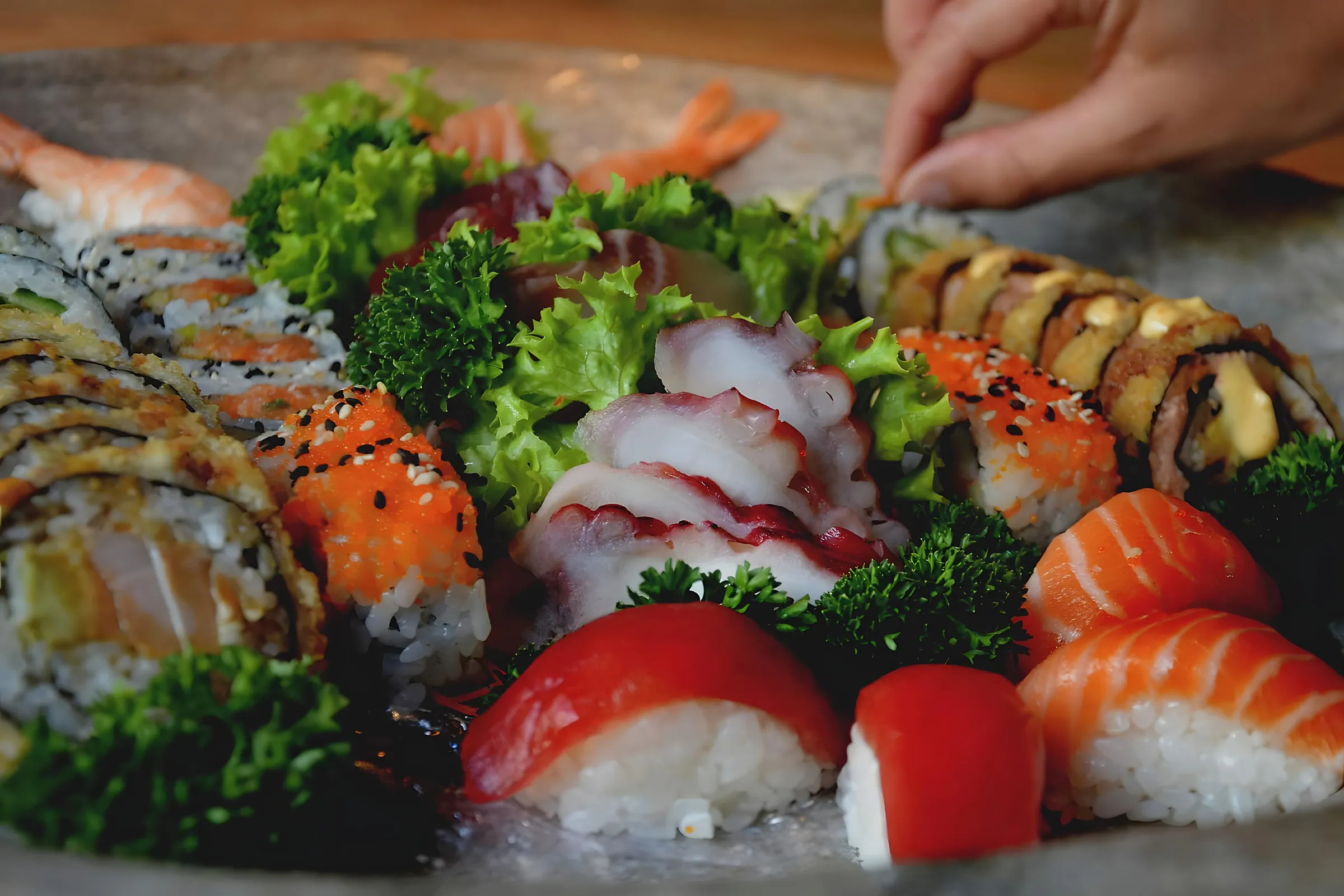 Een hand die nigiri schikt op een schotel